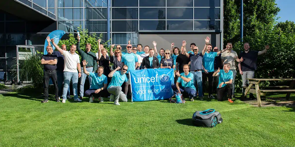 GARDENA x UNICEF Relay Run-team poseert met een UNICEF-banner voor een kantoorgebouw